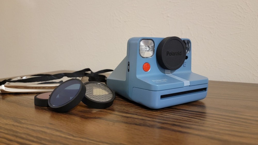 Polaroid instant camera, lenses, and packet of instant film