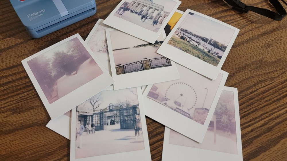 pile of instant photos on a wooden desk (1)