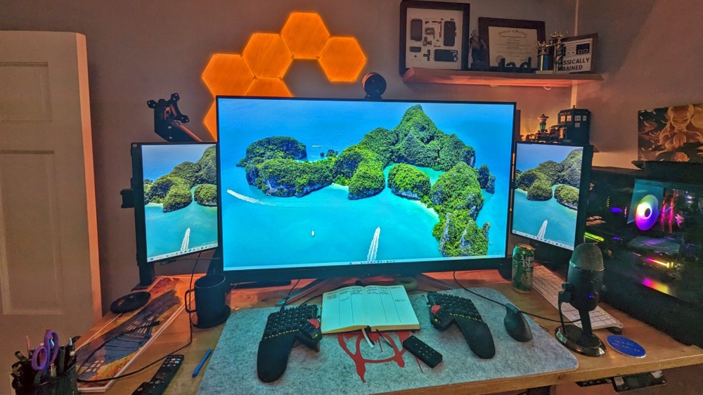 A large gaming monitor with two smaller monitors at the side